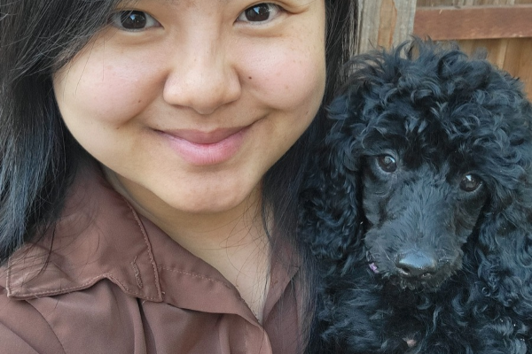 Girl holding black poodle puppy